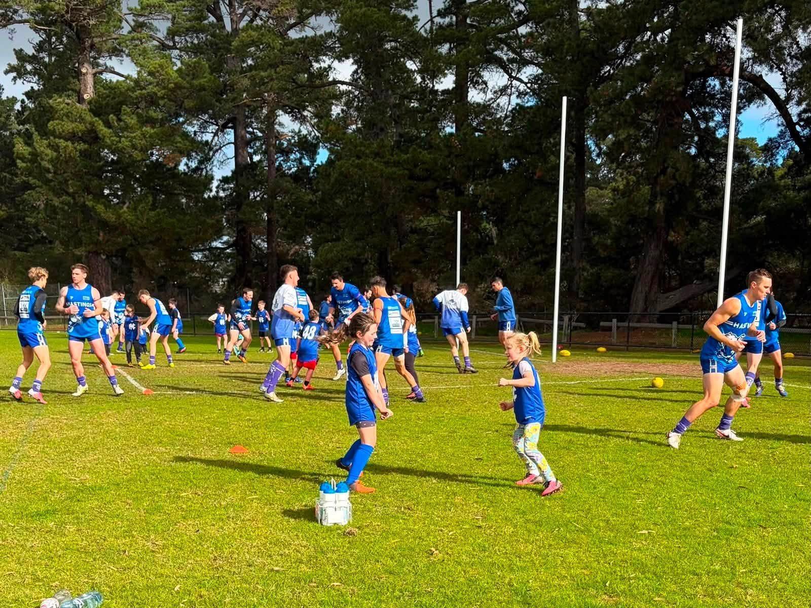 Juniors running drills on the Hastings Park oval on a sunny afternoon.